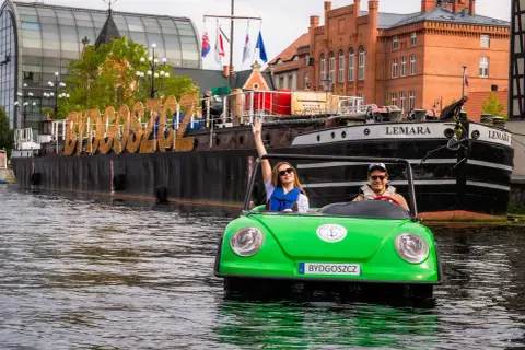 Para wodna w Bydgoszczy, na wodzie zielony samochodzik z parą turystów, na statku wielkie litery "BYDGOSZCZ". Idealne bydgoszcz wydarzenia kulturalne.